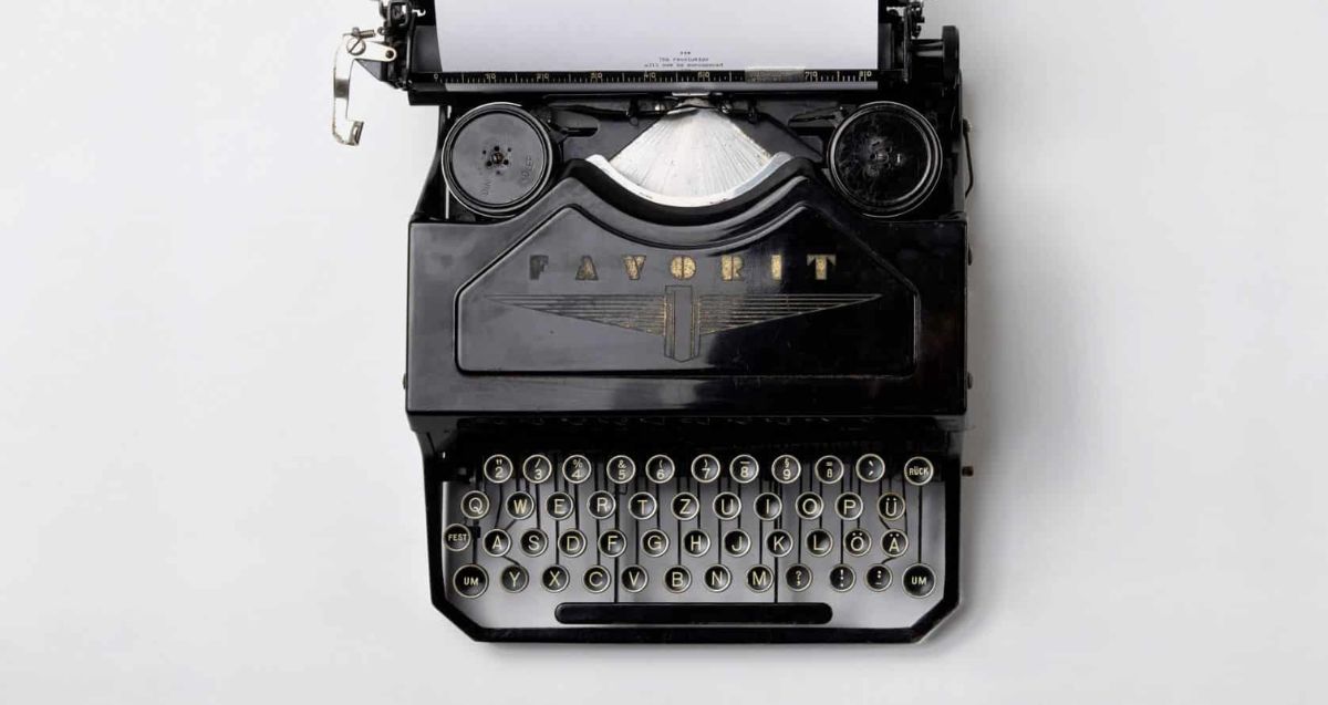 A black typewriter loaded with a sheet of white paper
